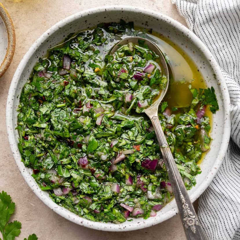 A bowl of Marina's fresh chimichurri with a serving spoon