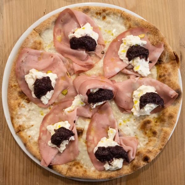 A pizza topped with mortadella, burrata and olive tapenade