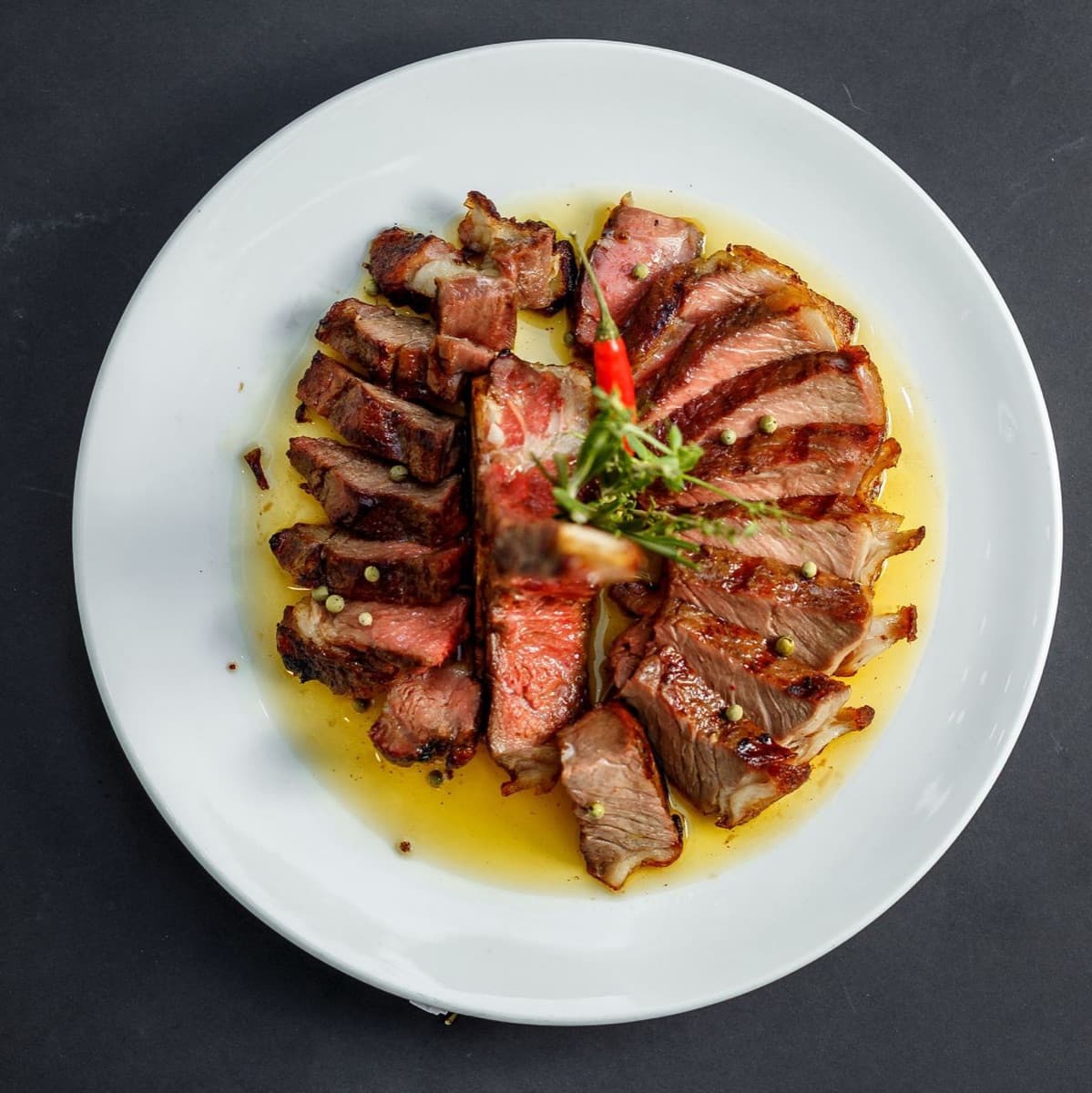 Sliced ribeye fanned across the plate and dressed in herb oil