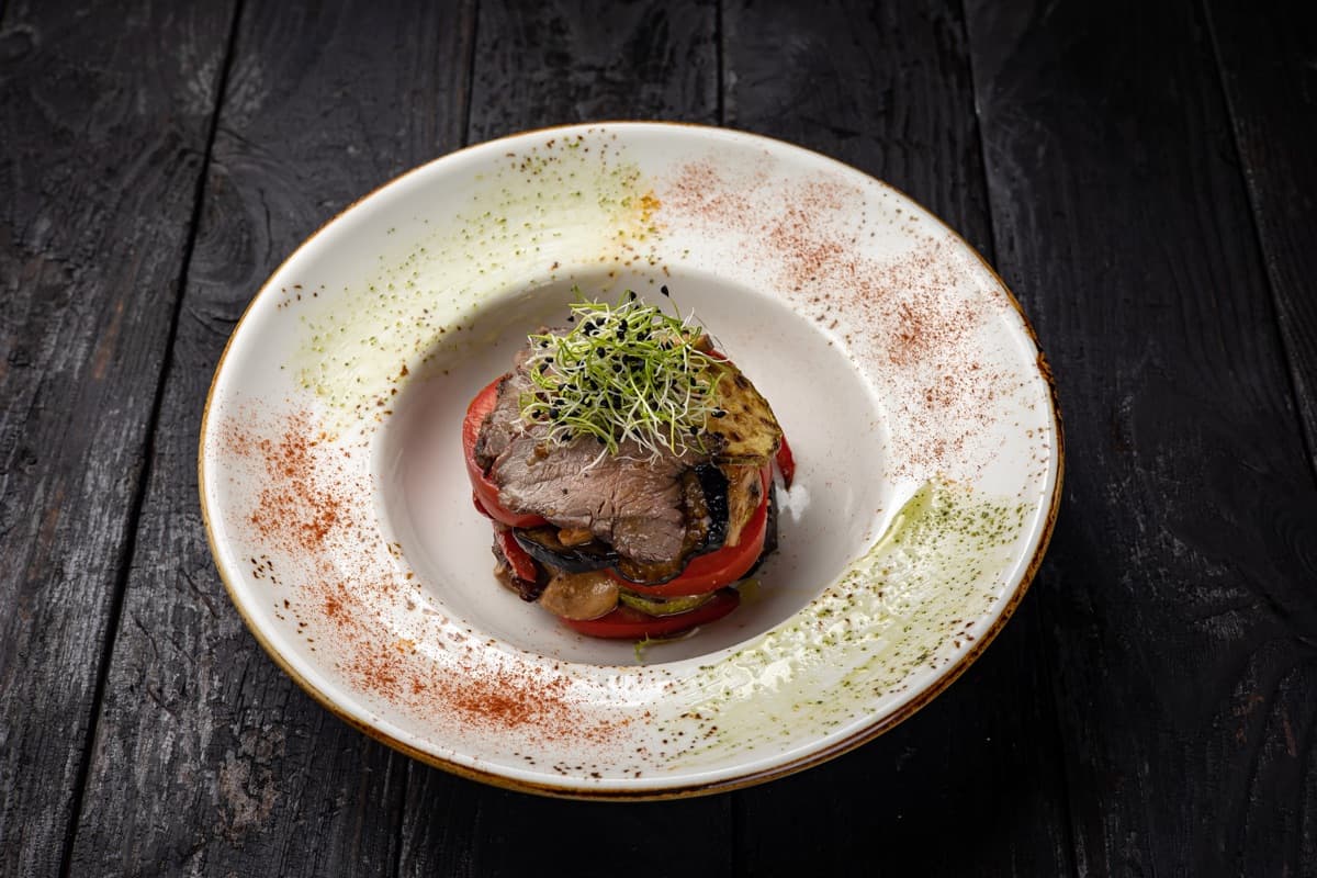 Beef and grilled eggplant plated with a herb oil dusting