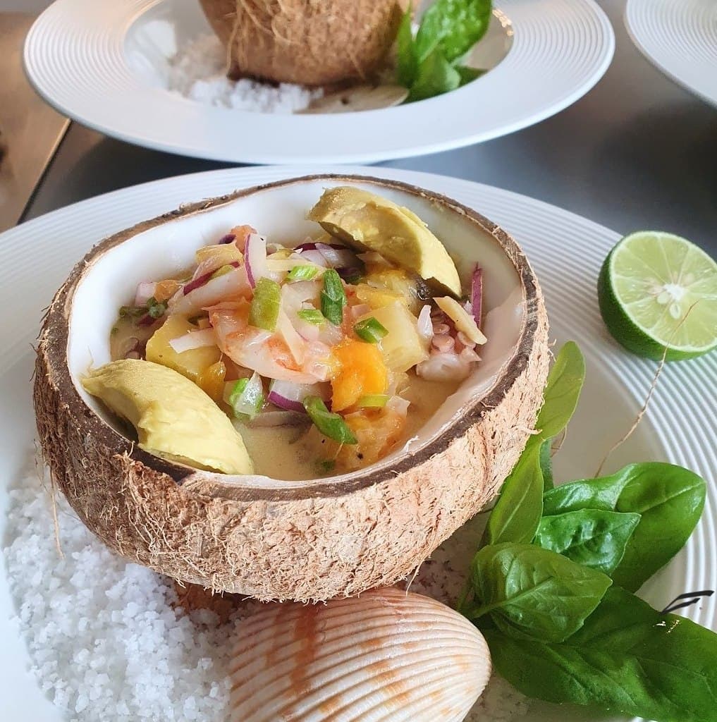 Ceviche served in a coconut shell with lime and herbs
