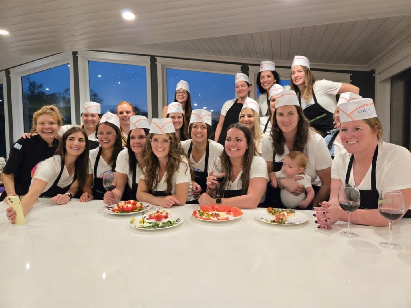 A team-building group in chef hats behind the dishes they cooked